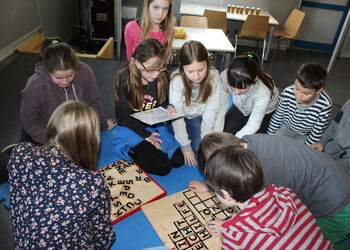 Eine Gruppe von SchülerInnen sitzen zusammen mit einer Lehrerin in einem Kreis.